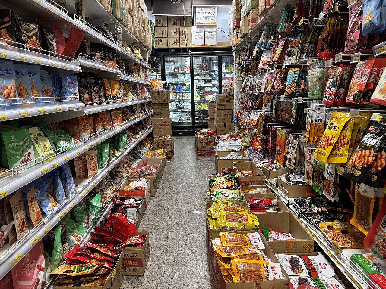 Shelves of packaged groceries lining a supermarket aisle.
