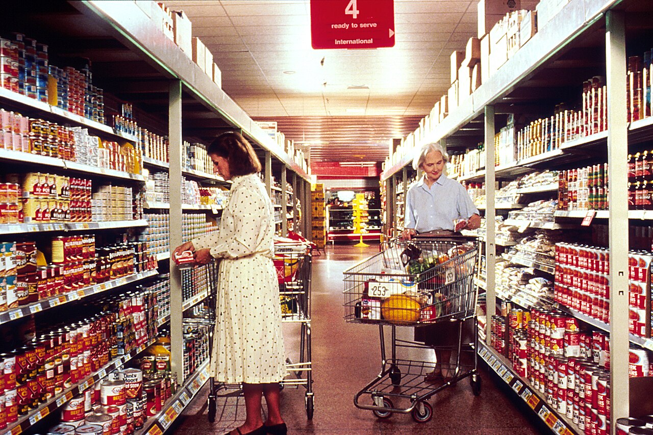 A shopper choosing food in a grocery store aisle.